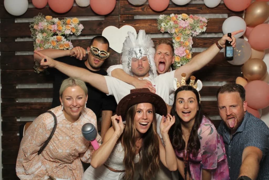 Party-Gäste mit Requisiten vor der Fotobox