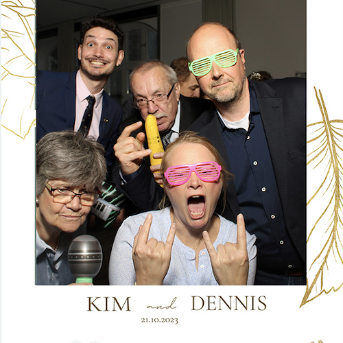 Gruppe von fünf Menschen bei der Hochzeit von Kim und Dennis, die mit lustigen Accessoires in die Kamera lächeln